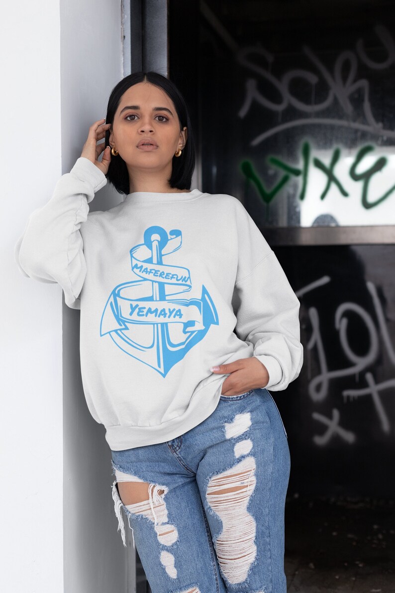 Puede incluir: Sudadera blanca con un gr&aacute;fico de ancla azul y el texto "Maferefun Yemaya" en una cinta blanca.