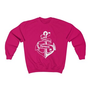 Puede incluir: Una sudadera rosa con un gr&aacute;fico de ancla blanca. El ancla est&aacute; envuelta con una cinta que dice "Maferefun Yemaya".