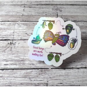 Puede incluir: Una pegatina colorida con una mariposa y el texto "Las cosas buenas valen la pena esperar!" La mariposa está rodeada de un círculo de imágenes que muestran las etapas del ciclo de vida de una mariposa, desde la oruga hasta la crisálida y la mariposa.