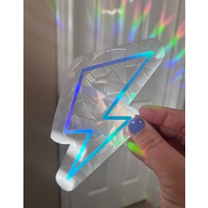 May include: A holographic sticker with a blue lightning bolt design. The sticker is iridescent and has a textured surface.