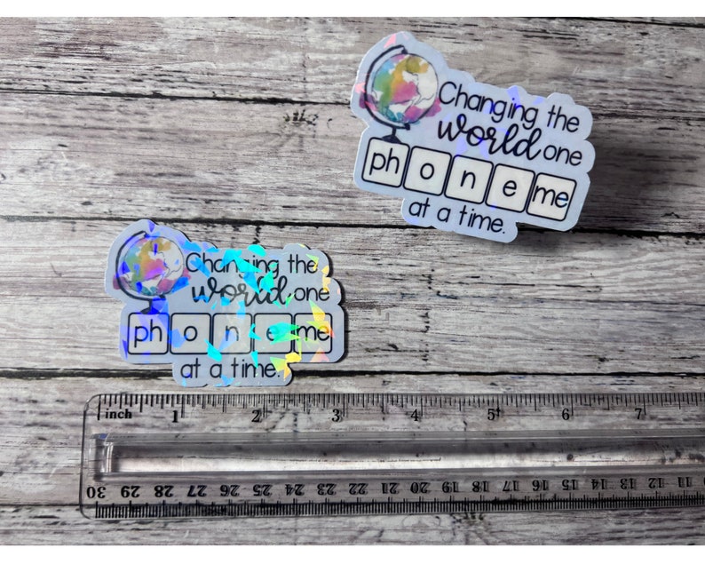 May include: Two iridescent stickers with a globe design and the text "Changing the world one phone me at a time."
