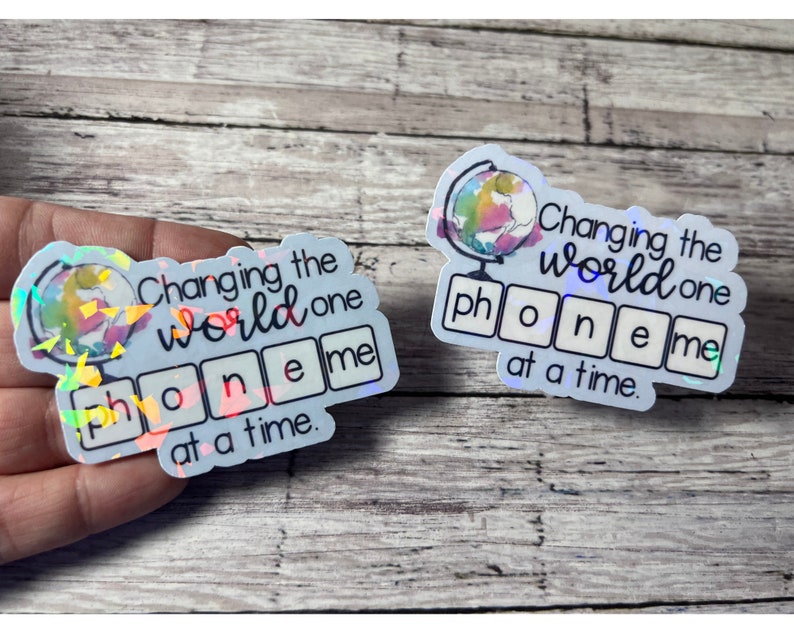 May include: Two iridescent stickers with the text "Changing the world one phoneme at a time." Each sticker features a globe graphic and the word "phoneme" spelled out in individual squares.