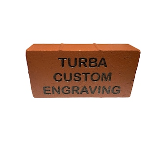 May include: A red brick with the text "TURBA CUSTOM ENGRAVING" engraved in black.