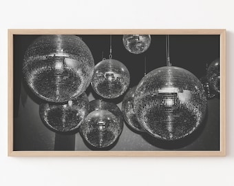 May include: A black and white photograph of multiple disco balls hanging from the ceiling. The disco balls are shiny and reflect light.