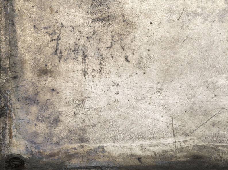May include: A close-up of a textured, light gray surface with scratches and marks. The surface has a worn and aged appearance.