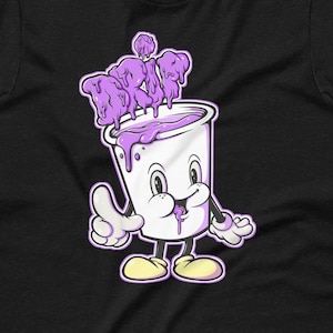 May include: Black t-shirt featuring a cartoon cup character with purple liquid spilling over the top. The cup has a smiling face and is giving a thumbs up. The word "DRIP" is written in purple on top of the cup.