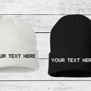 May include: Two knit beanies, one white and one black, with the text "YOUR TEXT HERE" embroidered on the front.