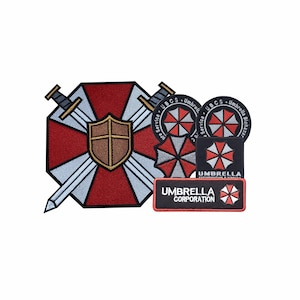 May include: Embroidered patches featuring the Umbrella Corporation logo and related designs. The patches include a shield with crossed swords, a red and white umbrella logo, and the text "Umbrella Corporation."