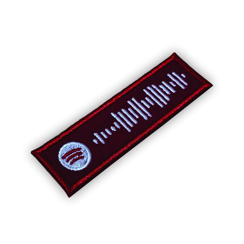 Op de afbeelding: Een rood en wit geborduurd patch met een Spotify-logo en een wit barcode-achtig ontwerp.