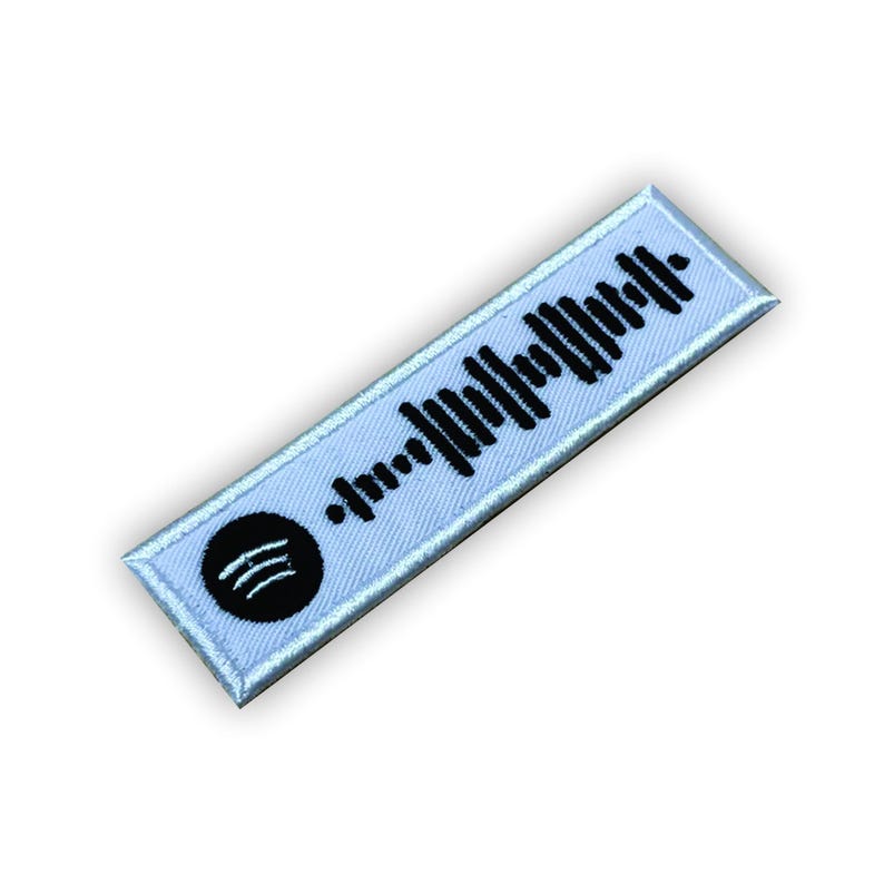 Op de afbeelding: Witte stoffen patch met een zwart Spotify-logo en een zwart-witte barcode.
