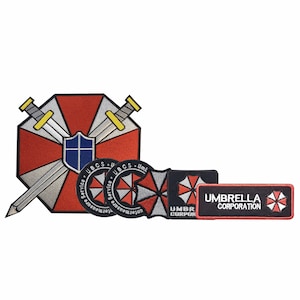 Peut inclure: Ensemble de quatre patchs brodés représentant le logo d'Umbrella Corporation de la série de jeux vidéo Resident Evil. Les patchs sont noirs, rouges et gris avec du texte blanc. Le plus grand patch représente un bouclier rouge et gris avec deux épées croisées.