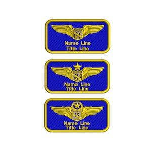 Puede incluir: Tres etiquetas de nombre bordadas en azul y dorado con el texto "Name Line Title Line". Las etiquetas presentan un águila dorada, una estrella dorada y un círculo dorado con una estrella.
