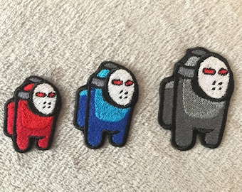 May include: Three embroidered iron-on patches featuring the Among Us character wearing a hockey mask. The patches are red, blue, and gray.