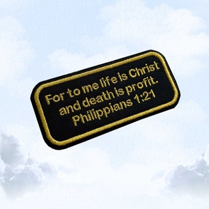 May include: Black embroidered patch with gold stitching. The text reads "For to me life is Christ and death is profit. Philippians 1:21".