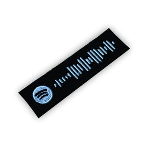Op de afbeelding: Zwarte stoffen patch met een wit Spotify-logo en een witte barcode.