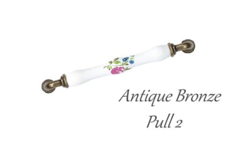 Pode incluir: Puxador de bronze antigo com um centro de cer&acirc;mica branca. A sec&ccedil;&atilde;o de cer&acirc;mica &eacute; decorada com um padr&atilde;o floral em rosa, azul e verde. O texto "Antique Bronze Pull 2" est&aacute; por baixo.