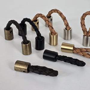 Può includere: Assortimento di terminali in corda di cuoio con punte metalliche in varie finiture, tra cui ottone, argento e nero. I cordini sono intrecciati e disponibili in marrone e nero.