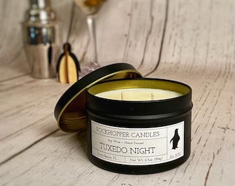 May include: A black candle tin with a gold lid. The candle is labeled "Rockhopper Candles" and "Tuxedo Night". The candle is soy wax and hand poured. The net weight is 6.5 oz (184g).
