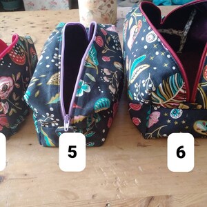 May include: Three fabric cosmetic bags with floral and leaf patterns on a black background. The bags have different colored zippers and interior linings. The bags are labeled with the numbers 4, 5, and 6.