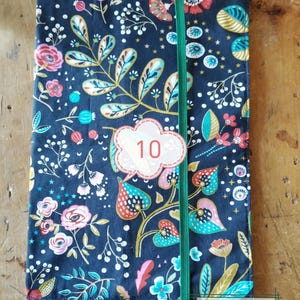 May include: A floral patterned notebook cover with a dark blue background. The cover features a green elastic band and a white label with the number 10. The notebook measures 8.27 inches by 11.69 inches.