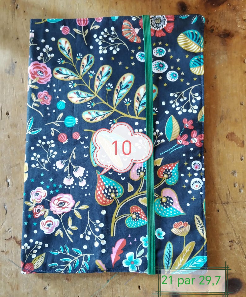 May include: A floral patterned notebook cover with a dark blue background. The cover features a green elastic band and a white label with the number 10. The notebook measures 8.27 inches by 11.69 inches.