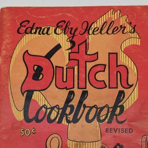 May include: A vintage cookbook cover with a red background and a yellow and orange illustration of a Dutch oven. The title is "Edna Ely Heller's Dutch Cooklook" with the price "50¢" and the word "REVISED" printed on the cover.