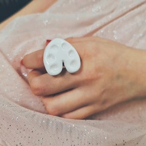 Peut inclure: Bague en céramique blanche en forme de palette de peinture avec six indentations circulaires.