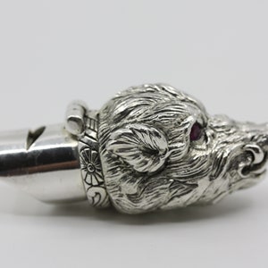 Può includere: Fischio d'argento con un designo dettagliato di testa di cinghiale. Gli occhi del cinghiale sono incastonati con pietre preziose rosse.