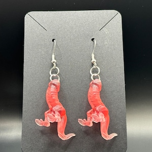 May include: A pair of dangle earrings featuring a translucent pink, 3D, anatomical design. The earrings are hanging from silver hooks.