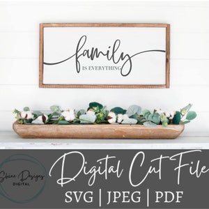 May include: A digital cut file for a sign that says "family is everything" in a cursive font. The sign is displayed on a white wall with a wooden frame. The image also includes a wooden bowl filled with cotton and greenery.