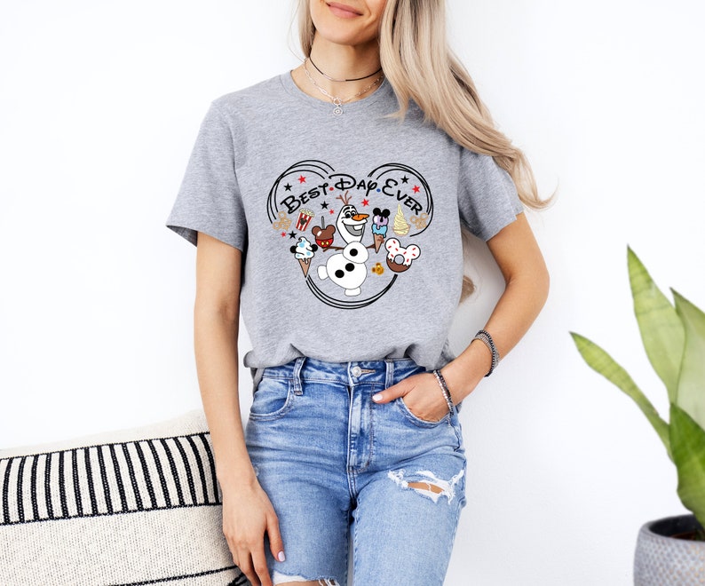 May include: Gray t-shirt with a Mickey Mouse ear design featuring Olaf from Frozen, Mickey Mouse, Minnie Mouse, and other Disney characters. The text "Best Day Ever" is written inside the Mickey Mouse ears.