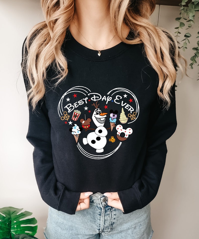 May include: Black sweatshirt with a white Mickey Mouse head design. The design includes the text "Best Day Ever" and various Disney characters and treats, including Olaf from Frozen.