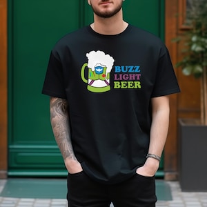 May include: A black t-shirt featuring a green beer mug graphic and the text "Buzz Light Beer" in blue, pink, and purple.