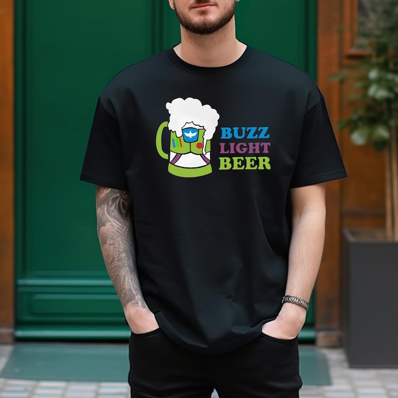 May include: A black t-shirt featuring a green beer mug graphic and the text "Buzz Light Beer" in blue, pink, and purple.