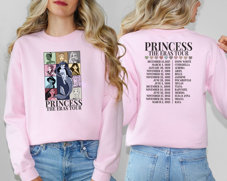 Puede incluir: Sudadera rosa con un gr&aacute;fico de princesas Disney en la parte delantera y una lista de princesas y sus fechas de estreno de pel&iacute;culas en la parte posterior. El texto en la parte delantera dice "Princess The Eras Tour". El texto en la parte posterior dice "Princess The Eras Tour".