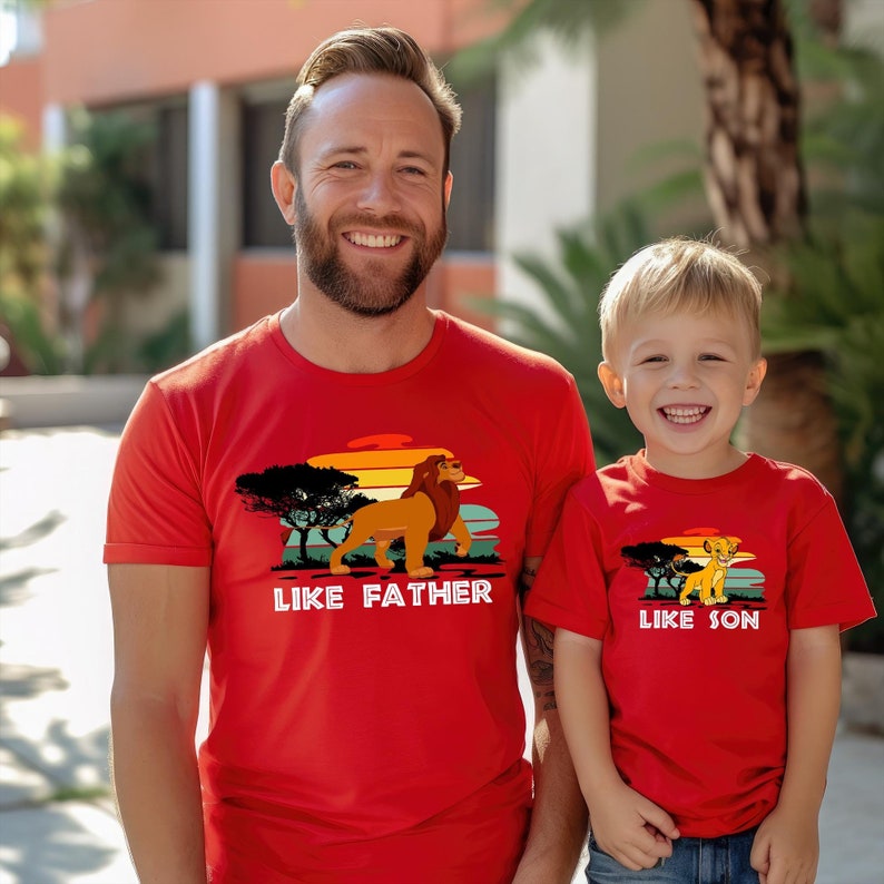 May include: Red t-shirts with a retro sunset graphic featuring a lion and the text "Like Father Like Son".