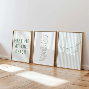 May include: Three framed art prints with a beach theme. The left print says "Meet Me At The Beach" in green text. The middle print features green line drawings of seashells. The right print shows a green line drawing of a bikini hanging on a clothesline.