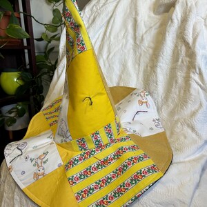 May include: A pointed hat constructed from patchwork fabric panels. The design features alternating sections of solid yellow fabric, yellow and white striped fabric with a floral pattern, and white fabric printed with small cartoon rabbit illustrations.