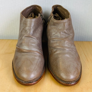 May include: A pair of brown leather ankle boots with a zipper on the side. The boots have a rounded toe and a low heel.