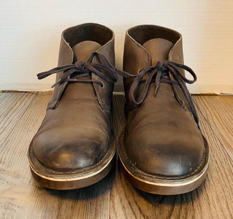 May include: A pair of brown leather ankle boots with laces. The boots have a worn look and are tied with brown laces.