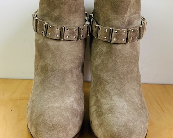 May include: A pair of gray suede ankle boots with silver buckle accents.