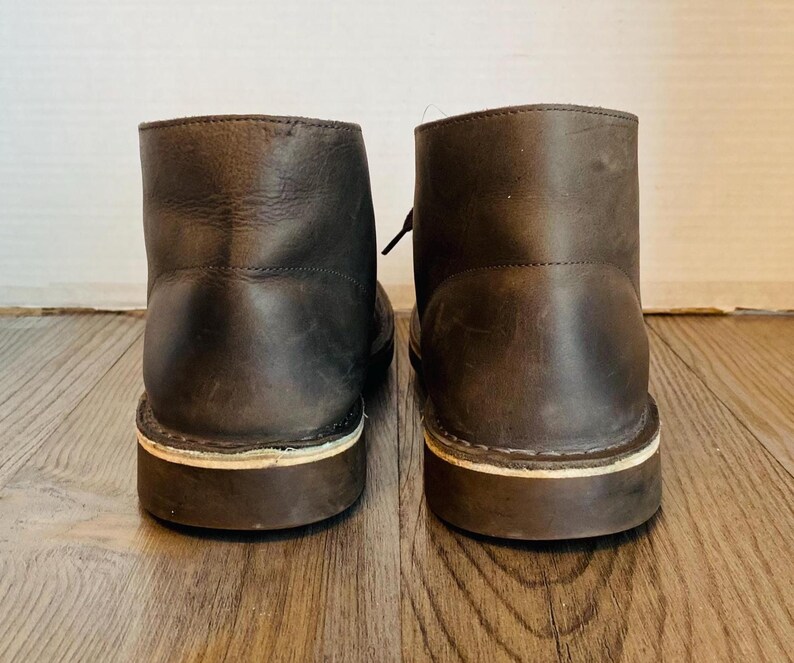 May include: A pair of brown leather ankle boots with white stitching around the soles.