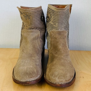 May include: A pair of light brown suede ankle boots with silver studs. The boots have a rounded toe and a low heel.