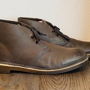 May include: A pair of brown leather desert boots with a cream colored sole.