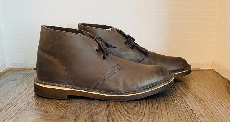 May include: A pair of brown leather desert boots with a cream colored sole.