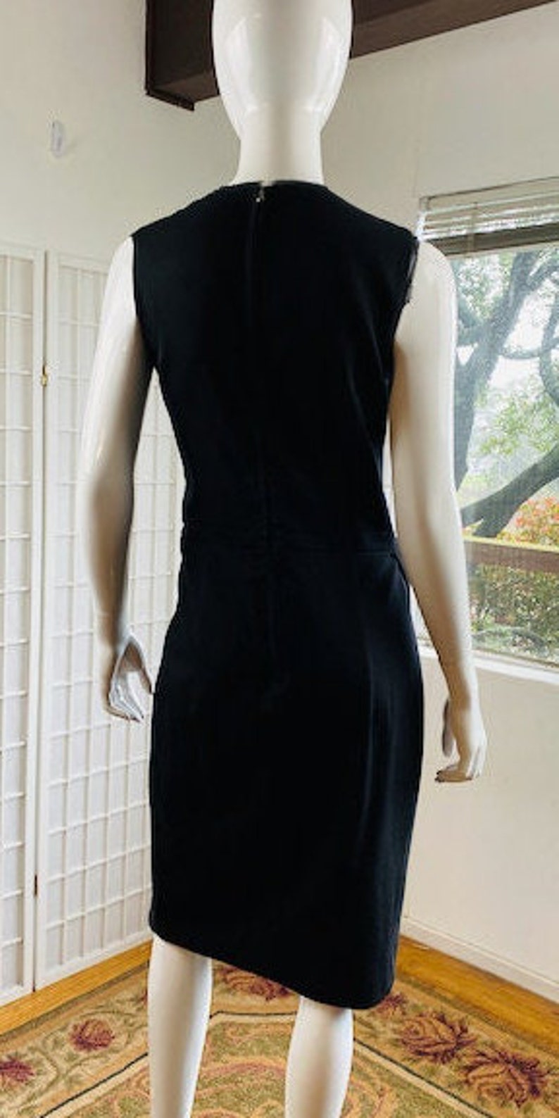 May include: A black sleeveless dress with a scoop neck and a zipper in the back.