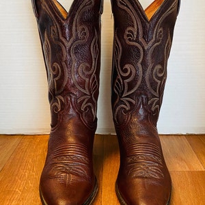 May include: A pair of brown leather cowboy boots with intricate stitching and a pointed toe.