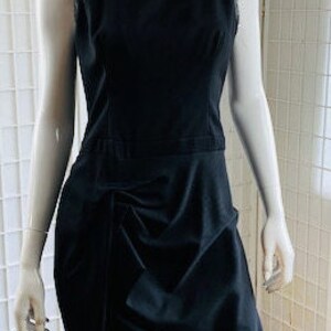May include: A black sleeveless dress with a gathered skirt and a simple neckline.