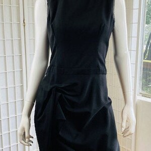 May include: A black sleeveless dress with a gathered skirt and a simple neckline.