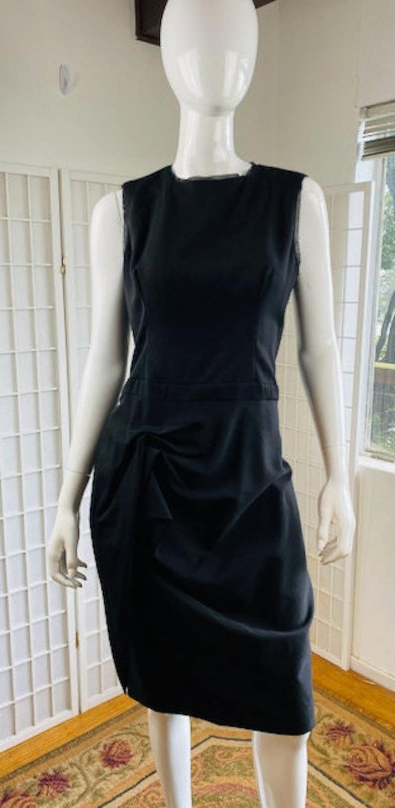 May include: A black sleeveless dress with a gathered skirt and a simple neckline.